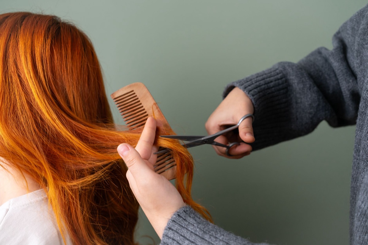 Stylist hands working on a mannequin head to demonstrate hair cutting techniques.