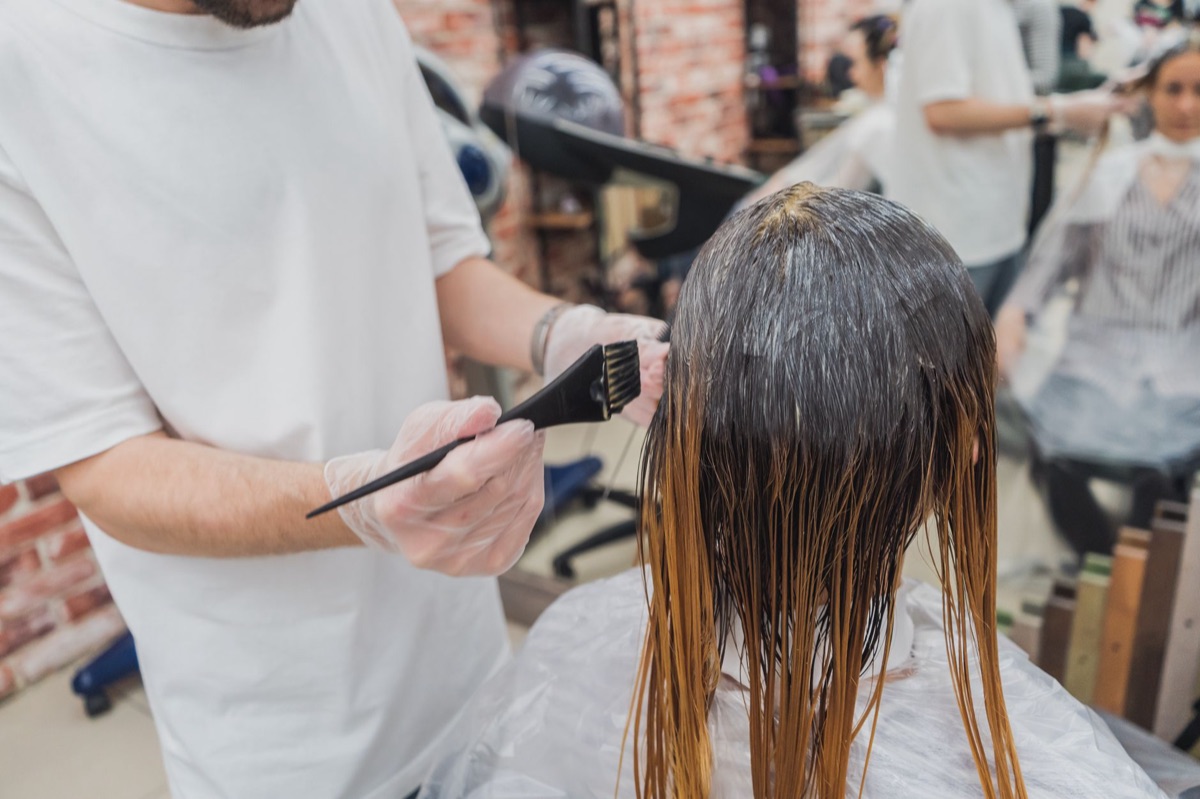 A hair dye brush and a bowl of hair dye on a white surface.